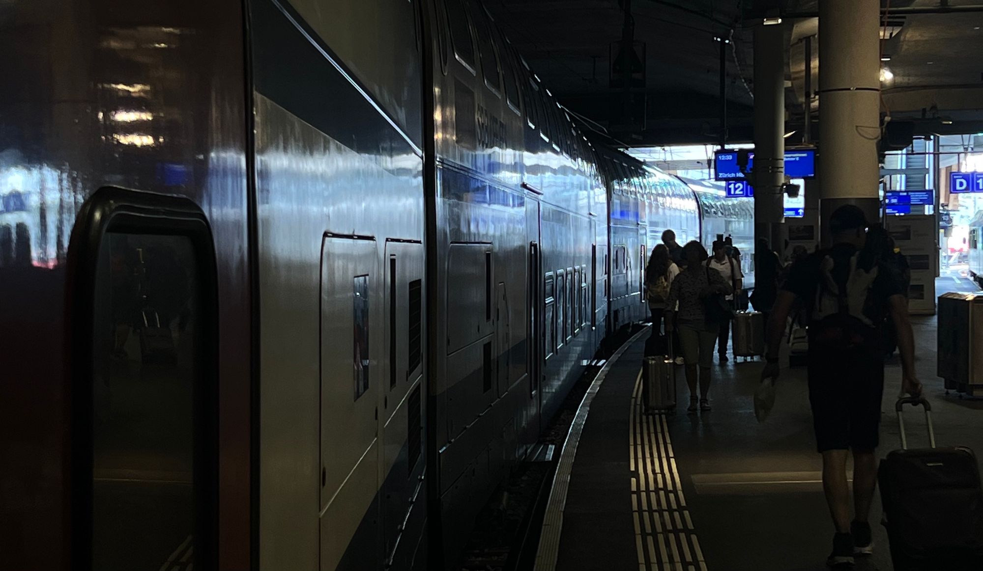 Perron am Bahnhof Bern, ein Zug auf der Linken Seite, Menschen steigen ein